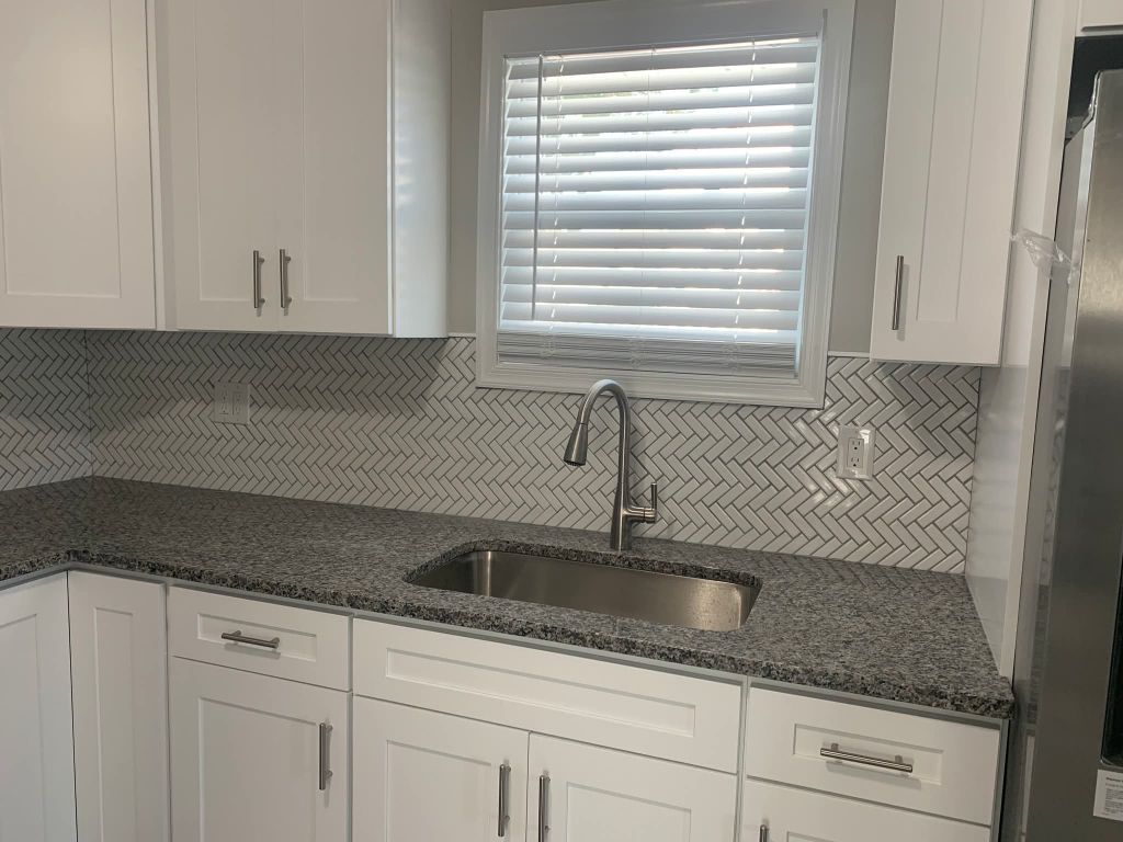 Kitchen with white herringbone tile backsplash and granite countertop