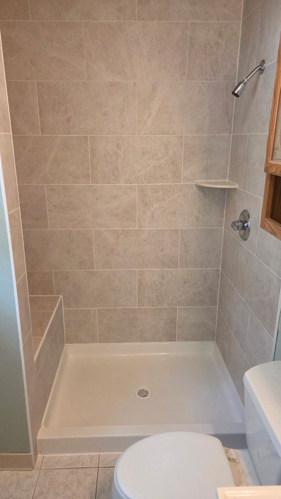 Finished tiled shower with new fixtures and built-in bench
